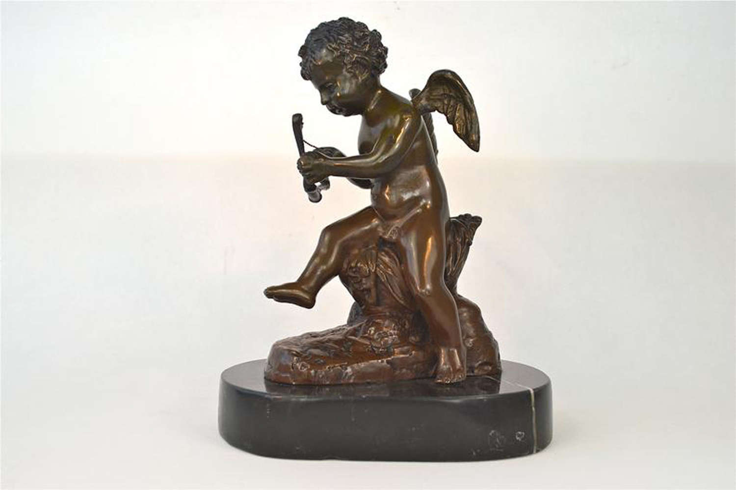 A beautiful seated Antique bronze cupid figure