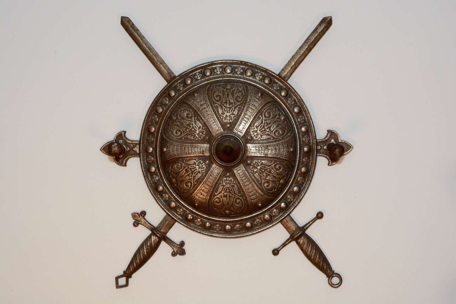 Hat and coat rack in the form of a round shield with crossed swords
