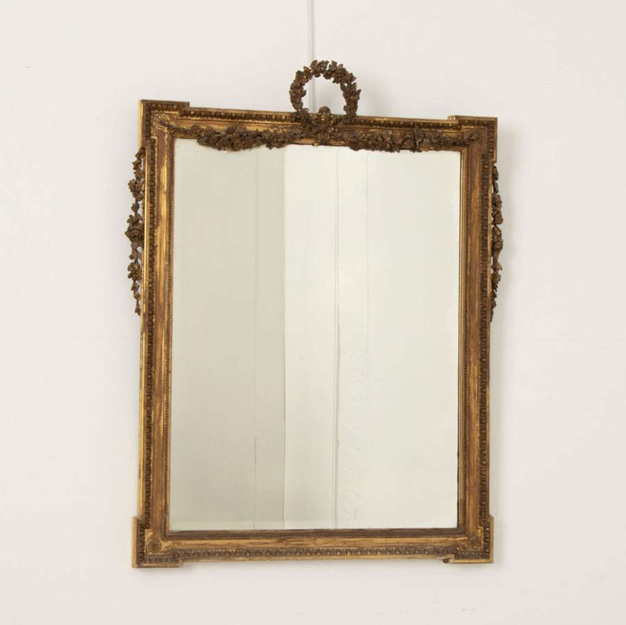 An antique bevelled French mirror with a water-gilded frame